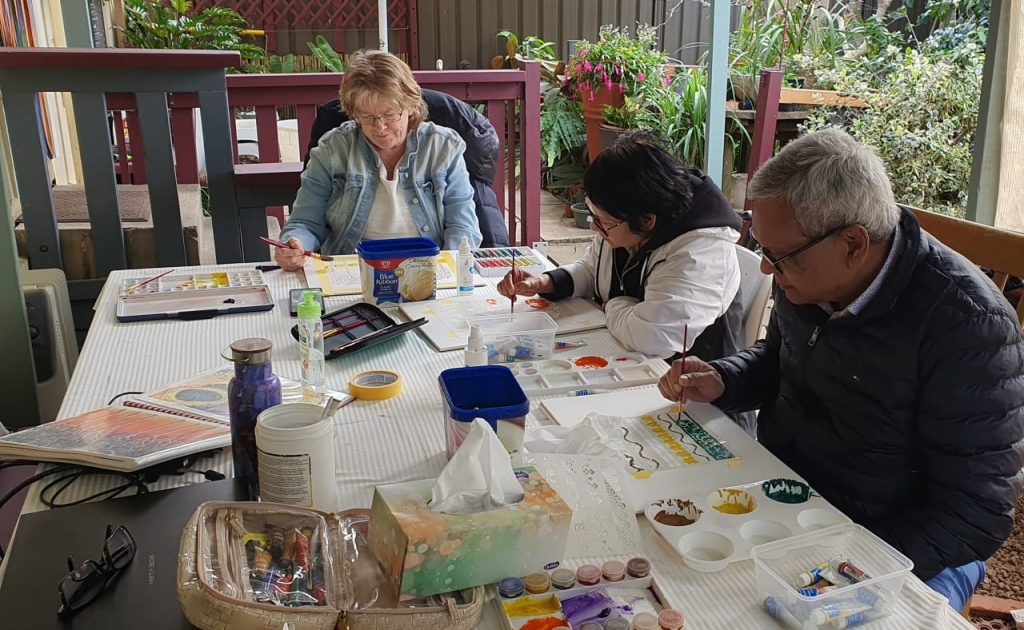 A photo of students focusing on artworks in the Cviisual Art Studio outdoor workspace.