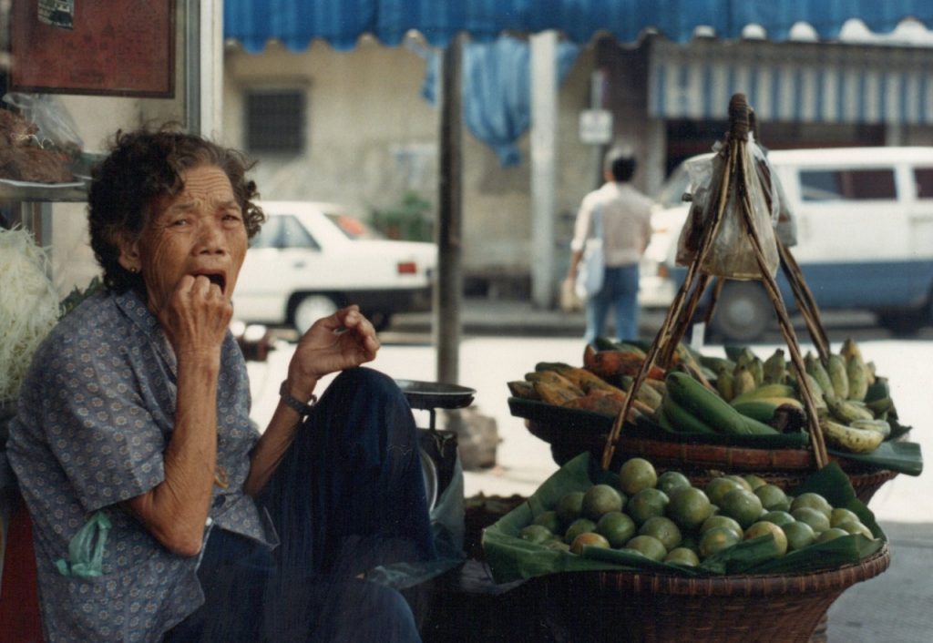A photo of an old lady selling fruits from the footpath in Bangkok.