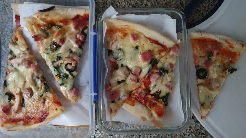 A photo of a home-made pizza getting portioned into containers - one for fridge, one for freezer.