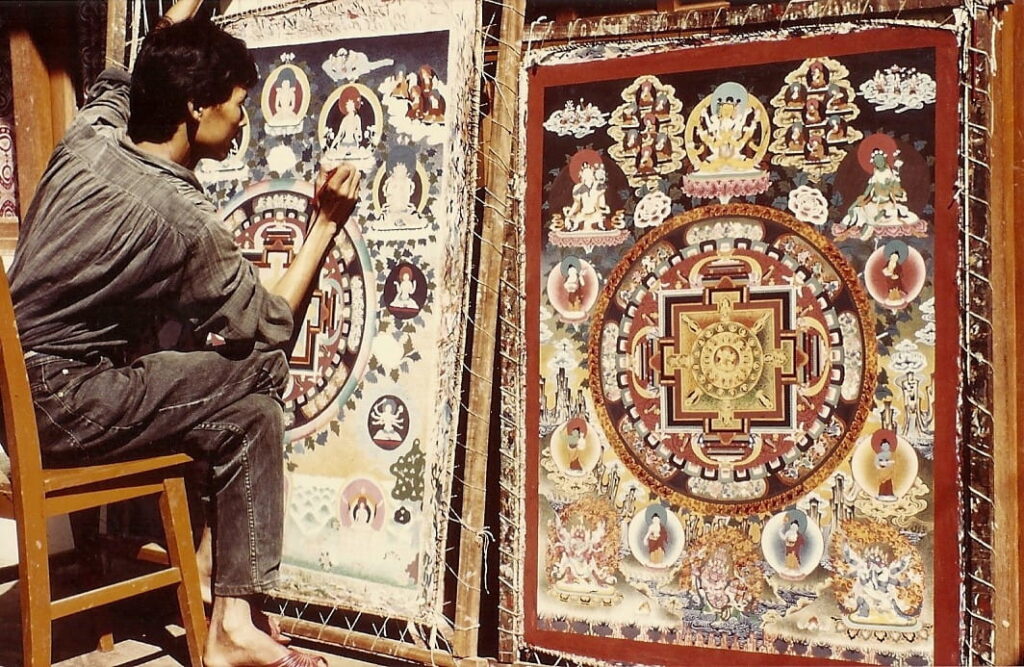 Robi the artist painting a large religious Thangka artwork in a market area - Kathmandu, Nepal.