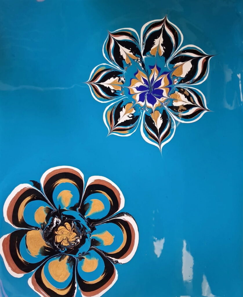 An acrylic flower pour painting with aqua blue background.