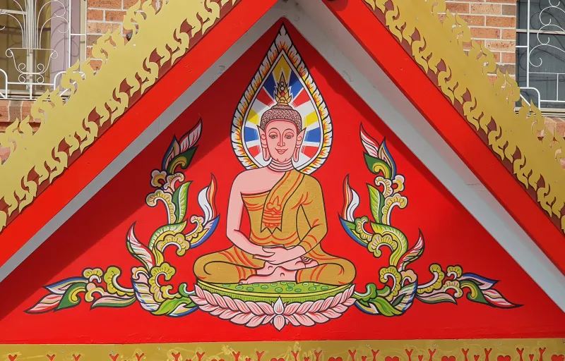 A photo of an acrylic hand-painted buddha figure on a fascia at a Thai Temple.